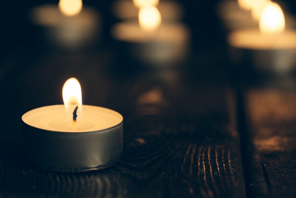 candles burning in darkness over black background. commemoration concept.