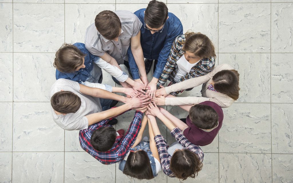 Young people with their hands together in a circle.